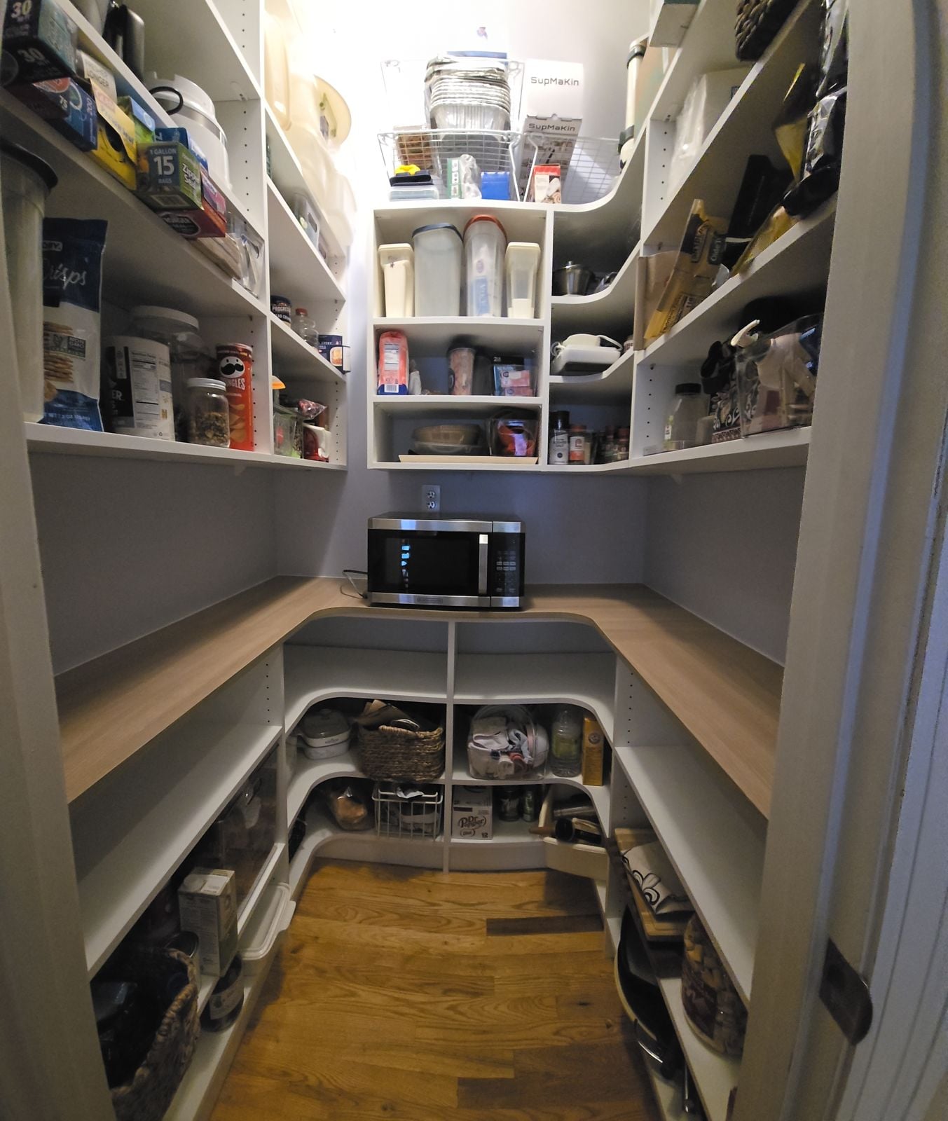 A walk-in pantry with white shelving and a butcher block counter